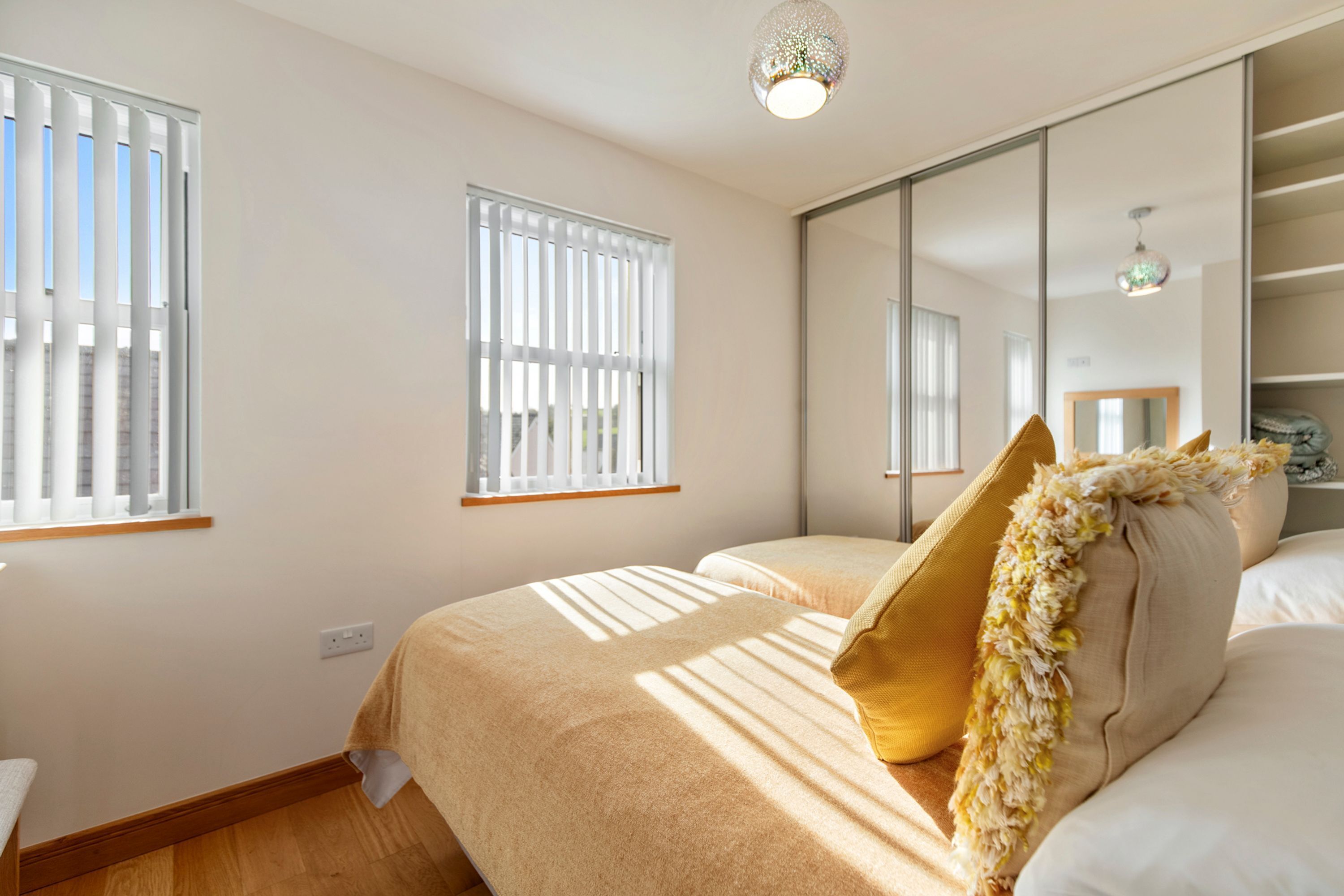 A bedroom with a bed, a window, a mirror, and a ceiling light fixture.