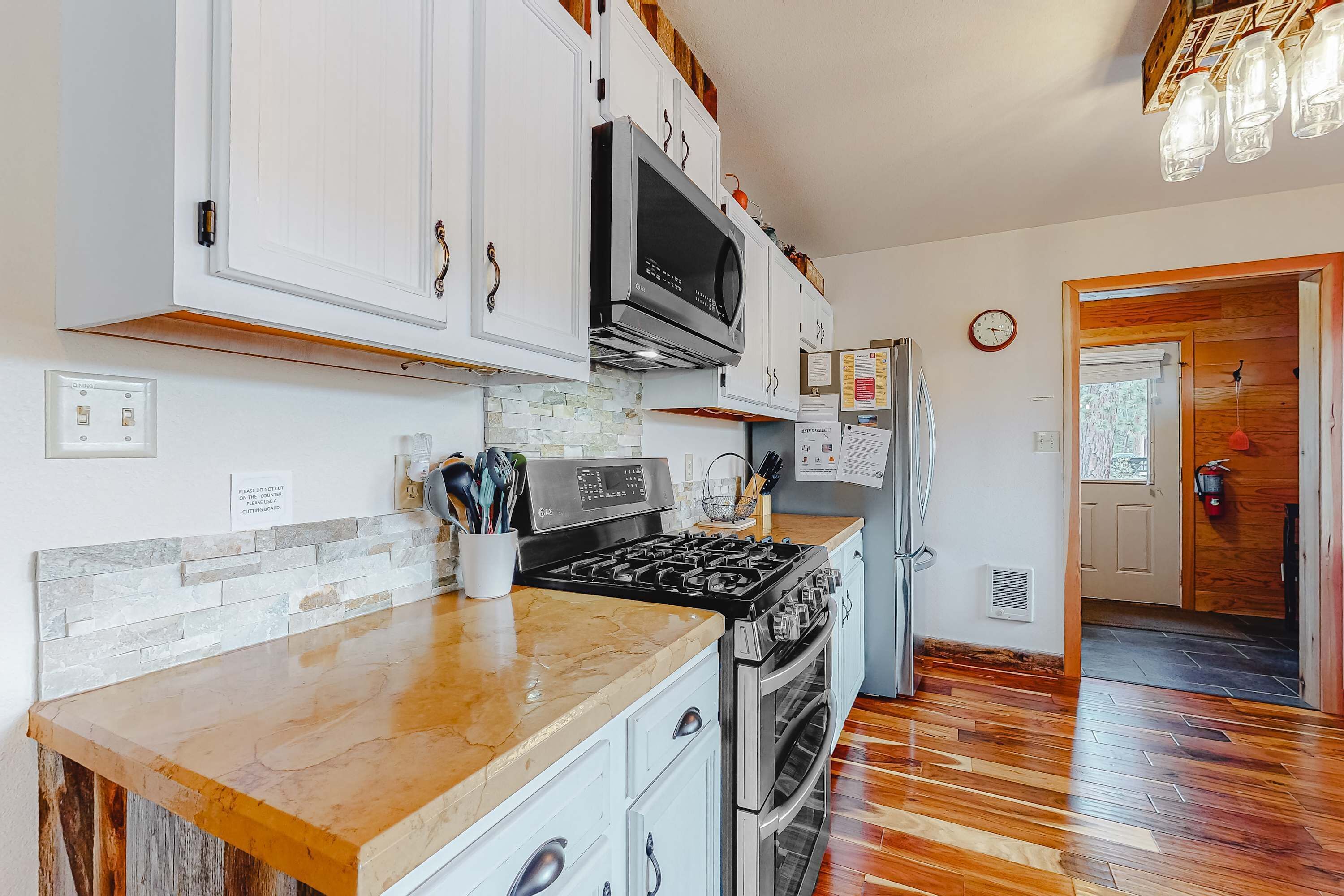 A kitchen with white cabinets, a stove, a microwave, and a refrigerator.