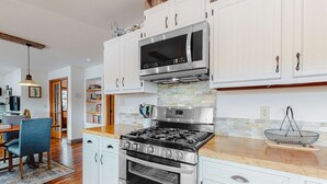 A kitchen with white cabinets, a stainless steel stove, an oven, and a microwave.
