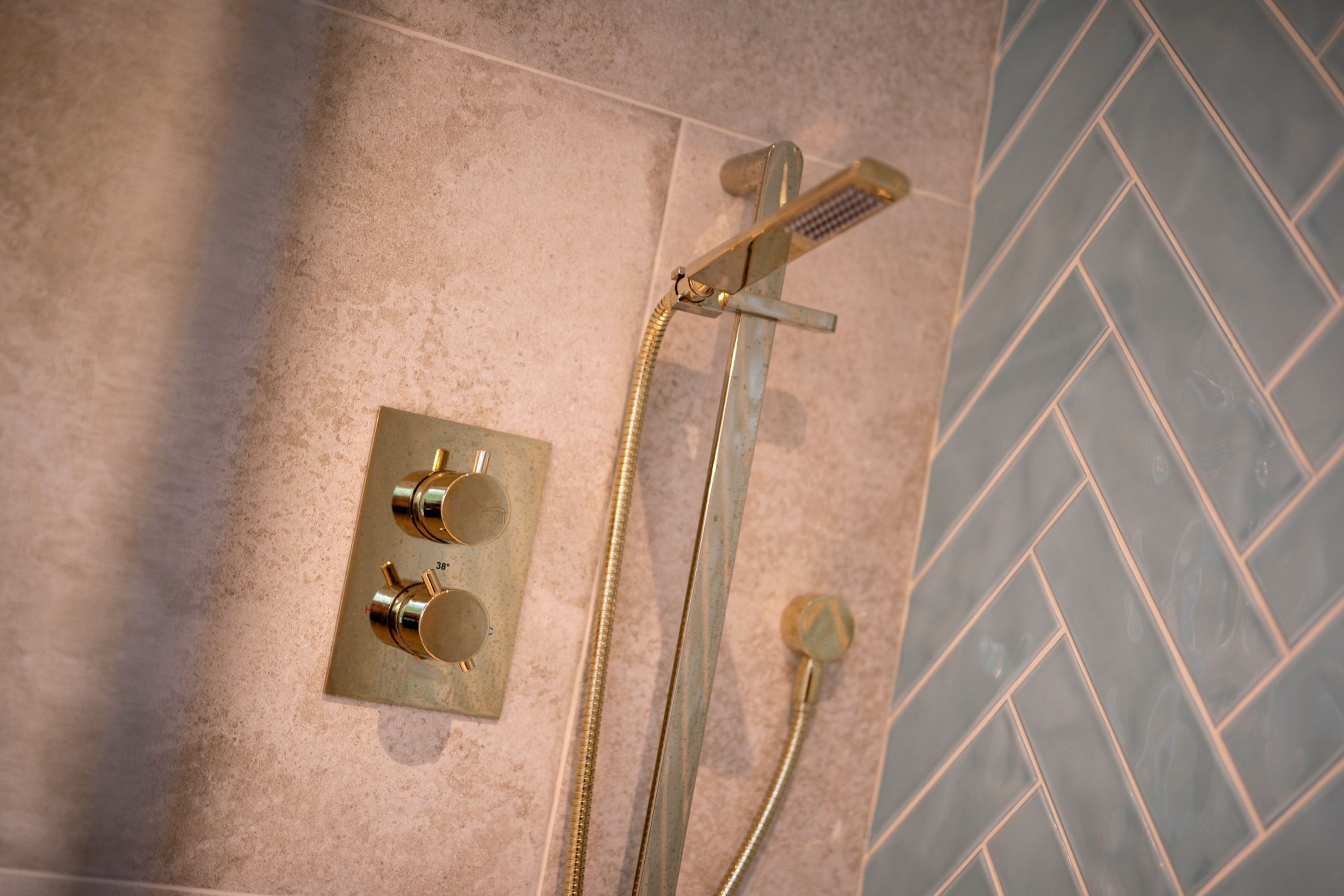 A shower with a handheld showerhead and a wall-mounted faucet, both with hoses.
