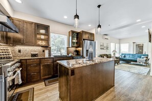 A modern kitchen with dark wooden cabinets, a central island, and pendant lighting. - Sunny apt with fireplace, partial water views, washer/dryer, grill & AC (Gold Beach)