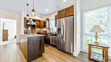 A modern kitchen with stainless steel appliances, wooden cabinets, and a large island.