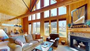 A wooden interior with a fireplace, a sofa, a coffee table, and a dining area. - Golf course-view chalet with fireplace, pools, tennis, gym, golf, volleyball (Eagle Crest)