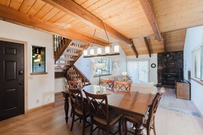 A spacious dining area with a wooden table and chairs, a staircase with wooden railings, and a stone fireplace. - Inviting condo with private sauna & wonderful shared amenities (Sunriver)