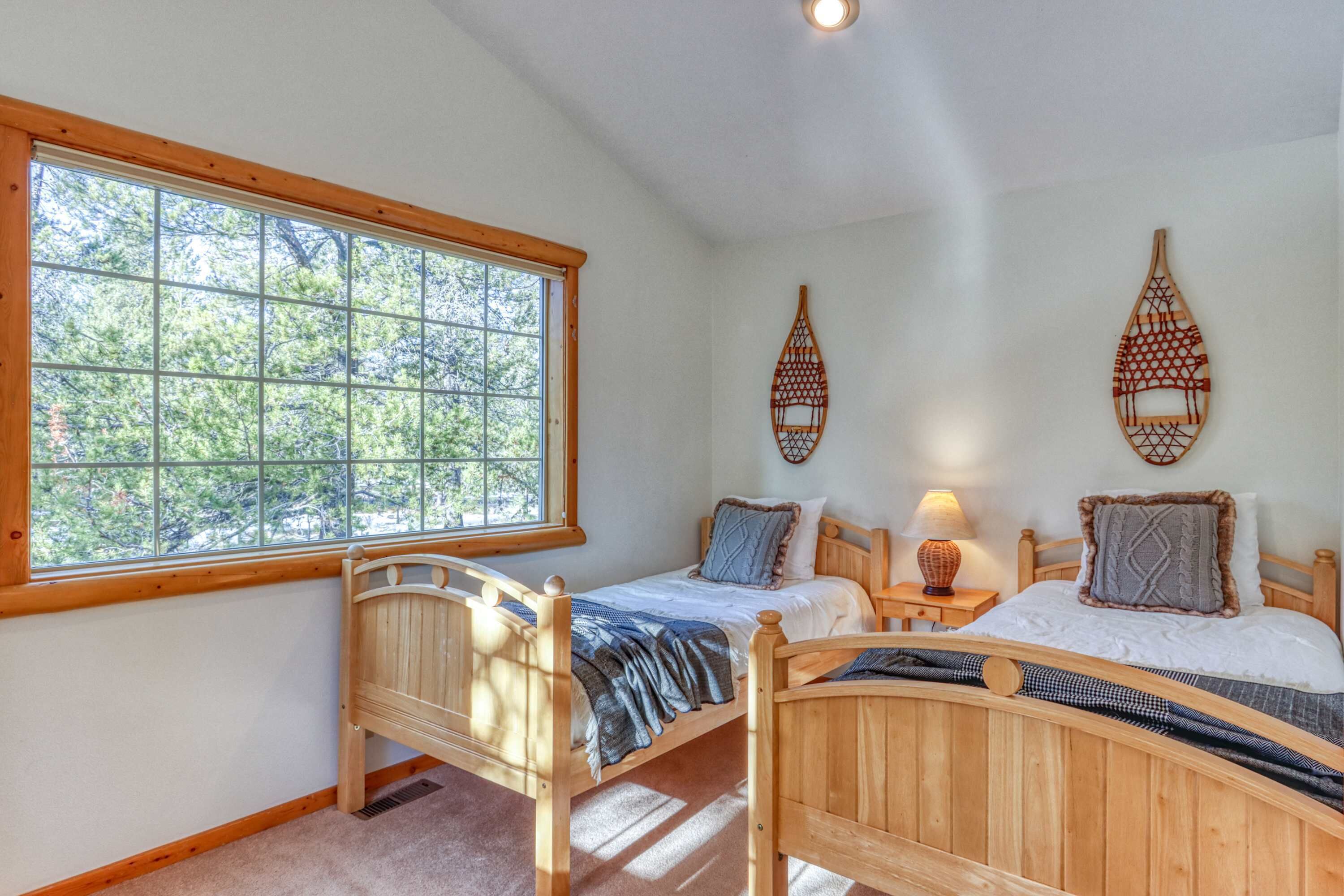 Een slaapkamer met twee houten bedden, een raam en wanddecoratie.