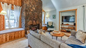 Ein gemütliches Wohnzimmer mit Kamin aus Stein, einem großen Fernseher und bequemen Sitzmöglichkeiten.