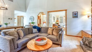 Ein großzügiges Wohnzimmer mit einer Eckcouch, einem runden Couchtisch und einem großen Spiegel, der den Raum widerzuspiegeln scheint.