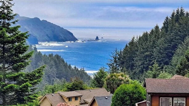A coastal house with a view of the ocean and mountains.