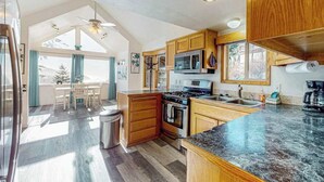 A modern kitchen with wooden cabinets, a granite countertop, and a dining area with a view.
