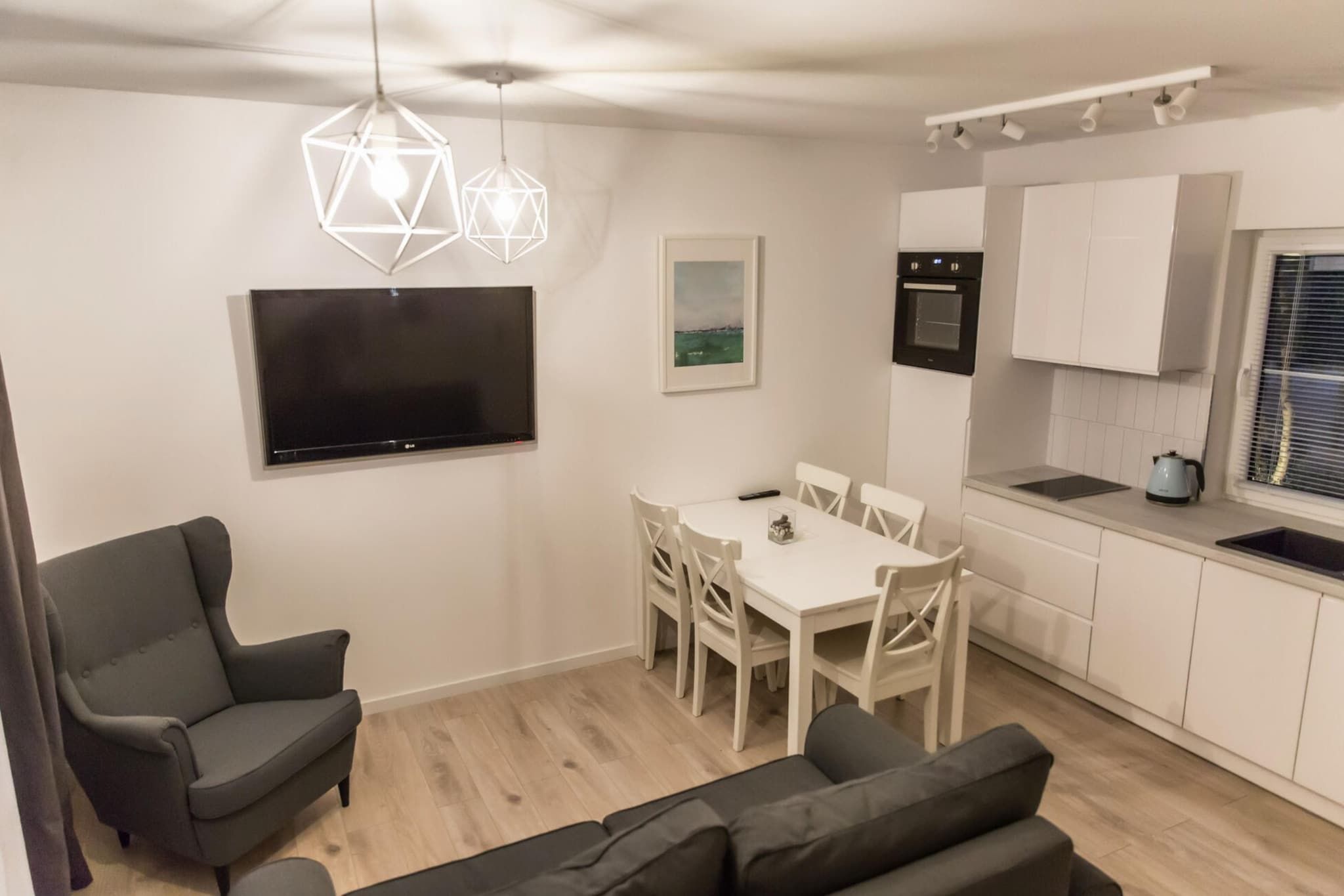 A modern apartment with a dining area, kitchen, and seating space.