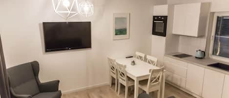 A modern apartment with a dining area, kitchen, and seating space.