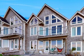 A multi-story residential building with a symmetrical facade, large windows, and a balcony on the second floor.