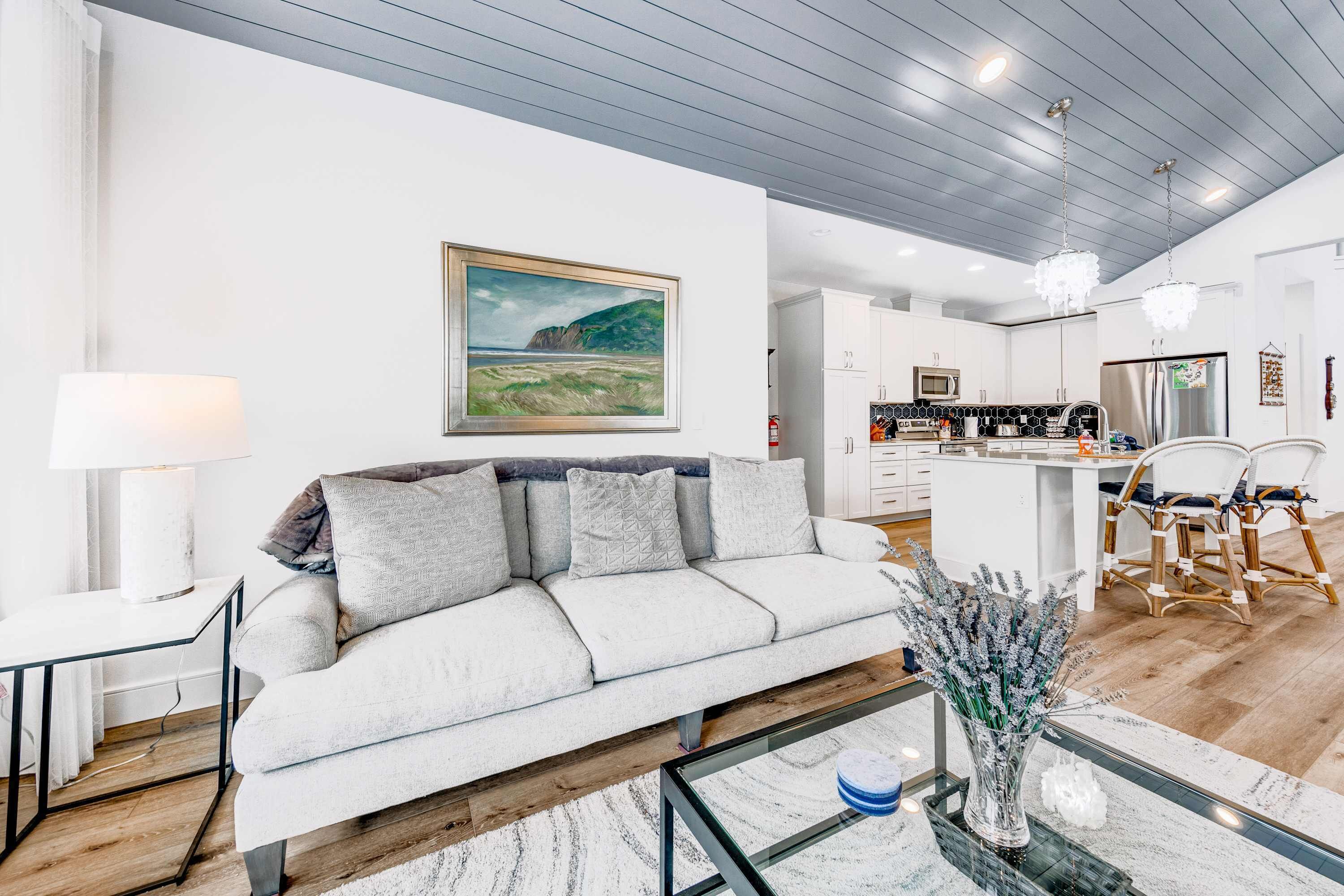 Un salon moderne avec un canapé, une table basse, une lampe et un tableau au mur.
