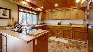 Une cuisine avec des meubles de rangement en bois, un îlot central, une fenêtre et un réfrigérateur.