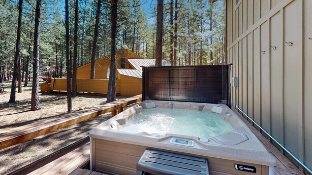 Un bain à remous à l’extérieur d’un chalet, entouré d’arbres.