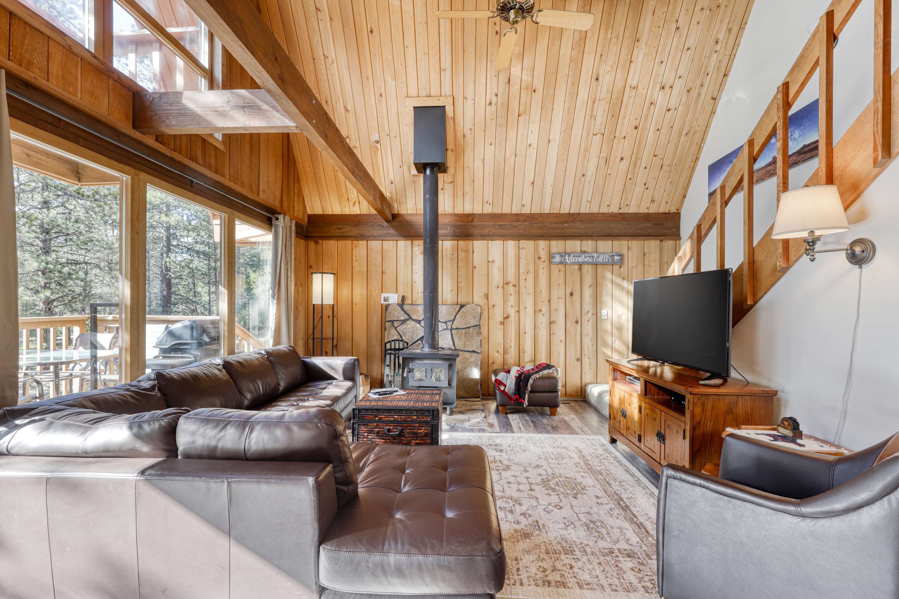 Een houten interieur met een grote bank, een televisie en een stenen open haard.