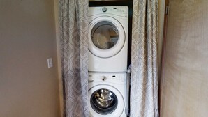 A laundry room with two stacked washing machines, a metal rod, and patterned curtains. - Wonderful Home Close to Lake withPrivate W&D, WiFi, Gas Fireplace - 2 Dogs Okay (Joseph)