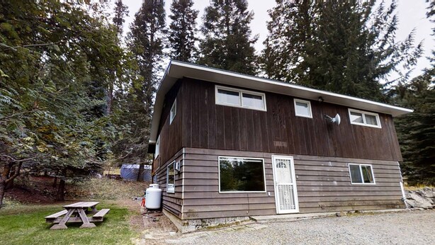 A two-story cabin with a sloped roof, a front porch, and a gravel driveway. - Wonderful Home Close to Lake withPrivate W&D, WiFi, Gas Fireplace - 2 Dogs Okay (Joseph)