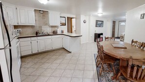 A kitchen with white cabinets, a wooden dining table, and a tiled floor. - Wonderful Home Close to Lake withPrivate W&D, WiFi, Gas Fireplace - 2 Dogs Okay (Joseph)