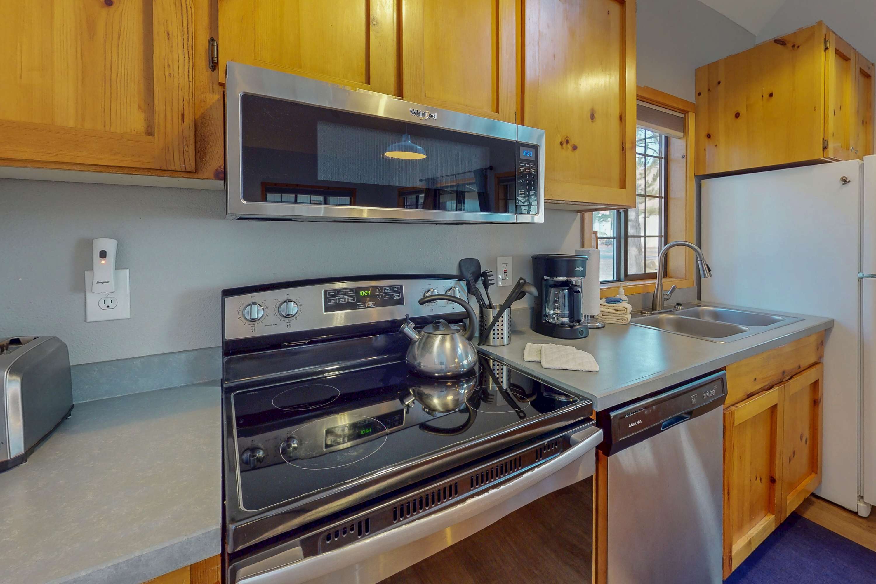 A kitchen with wooden cabinets, a stainless steel microwave, a stove, a dishwasher, and a sink.