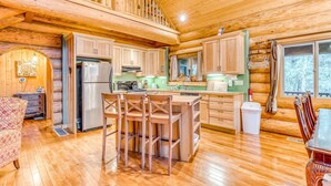 A wooden cabin interior with a kitchen, dining area, and a loft bedroom. - Woodland home near golf & ski slopes with wraparound deck - dog-friendly (Welches)