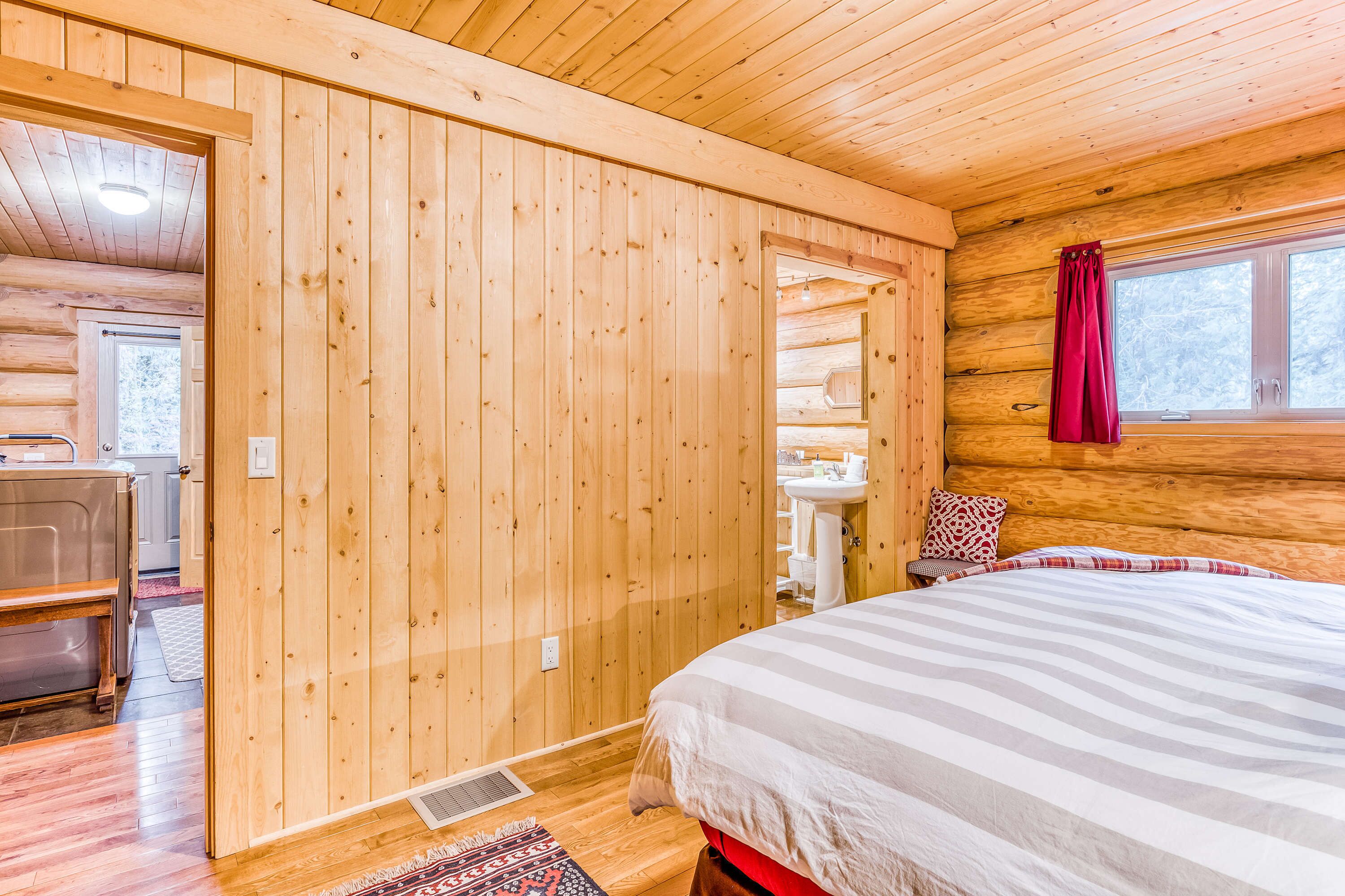 Ein Holzblockhaus-Innenraum mit einem Bett, einem Badezimmer und einem Essbereich.