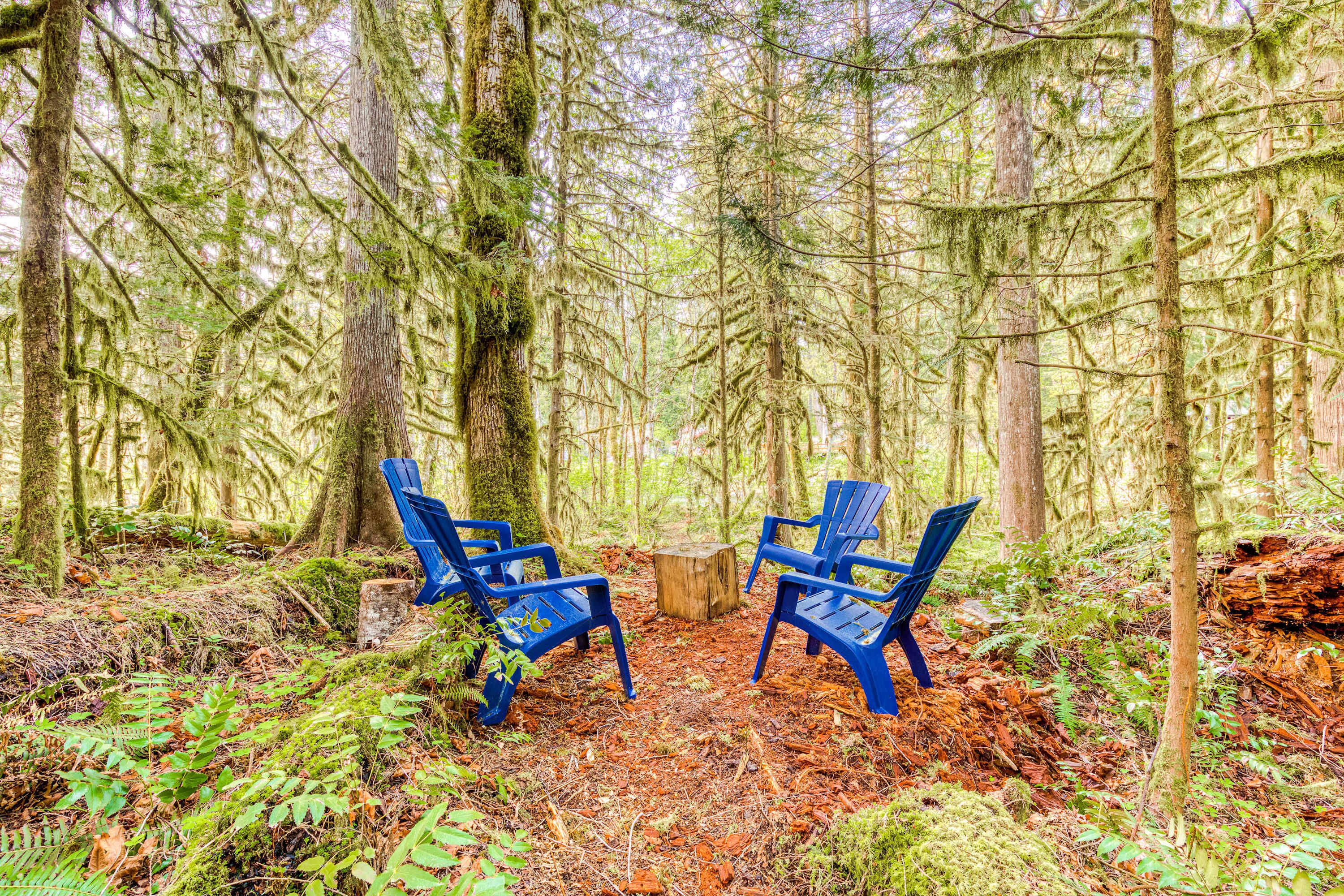 Escena de bosque con dos sillas azules y un tocón de madera.