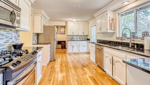 A modern kitchen with white cabinetry, a stainless steel range, and a wooden floor. - Spacious Home - Golf Course Views, Central AC, WiFi & Alfresco Living (Bend)