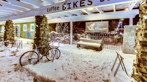 A snow-covered outdoor area with a bicycle, a bench, and a sign reading 'coffee BIKES beer'. - Spacious Home - Golf Course Views, Central AC, WiFi & Alfresco Living (Bend)