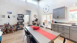 Une cuisine spacieuse avec un grand îlot central, un plafond en bois et une horloge au mur.