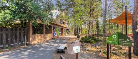 A nature center entrance sign, a wooden building, and a picnic table.