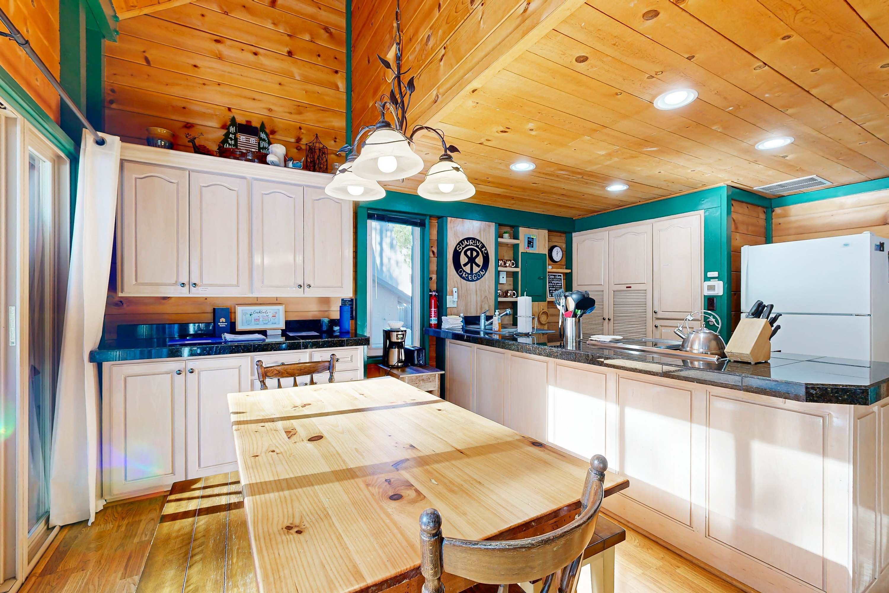 A wooden interior with a kitchen area, including cabinets, a dining table, and a refrigerator.