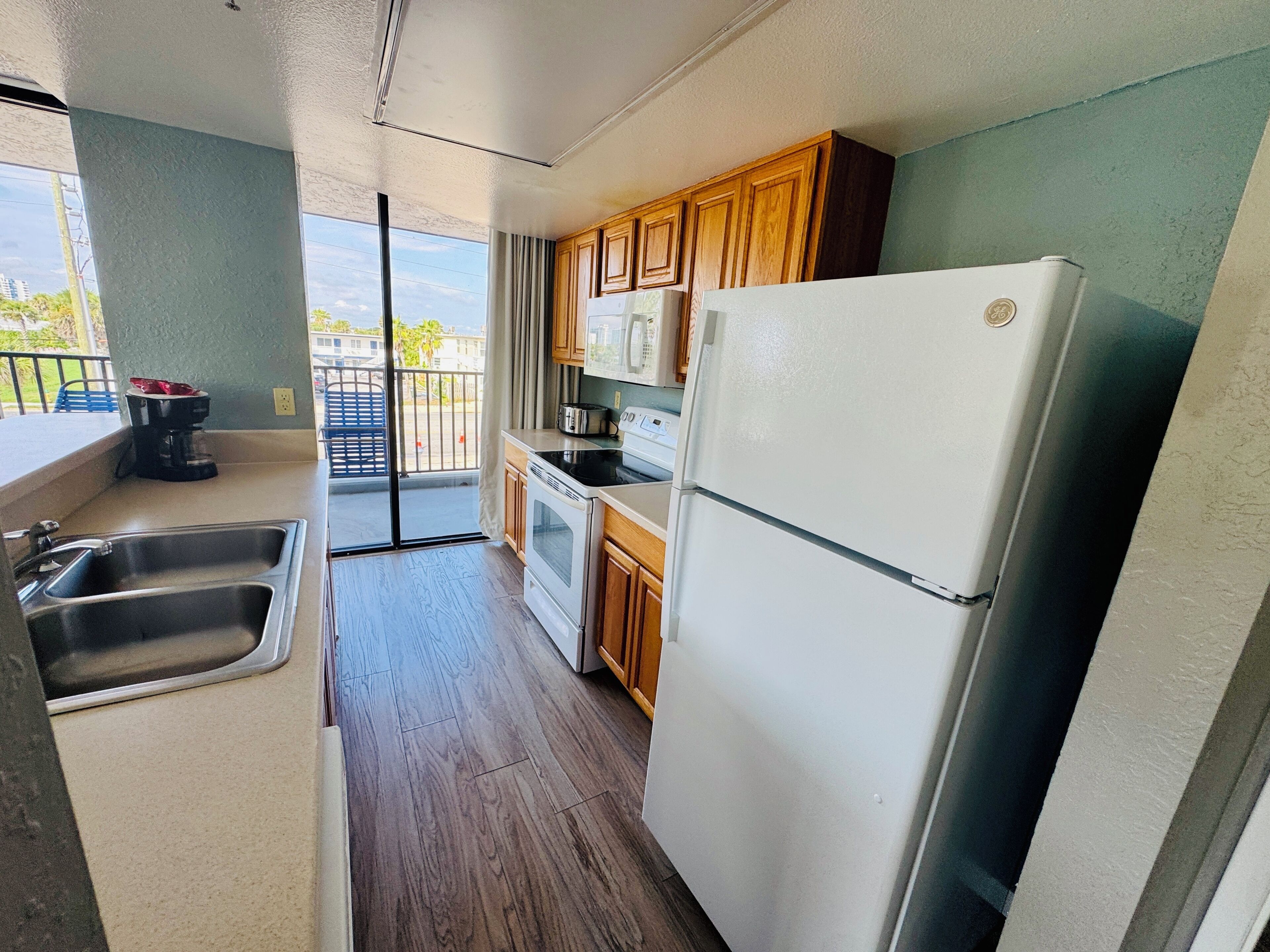 A kitchen with a refrigerator, oven, microwave, and a coffee maker.