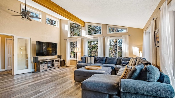 Een ruime woonkamer met een grote modulaire bank, een flatscreen televisie en een houten entertainmentkast.