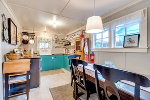 A kitchen with teal cabinets, a wooden dining table, and a hanging light fixture.