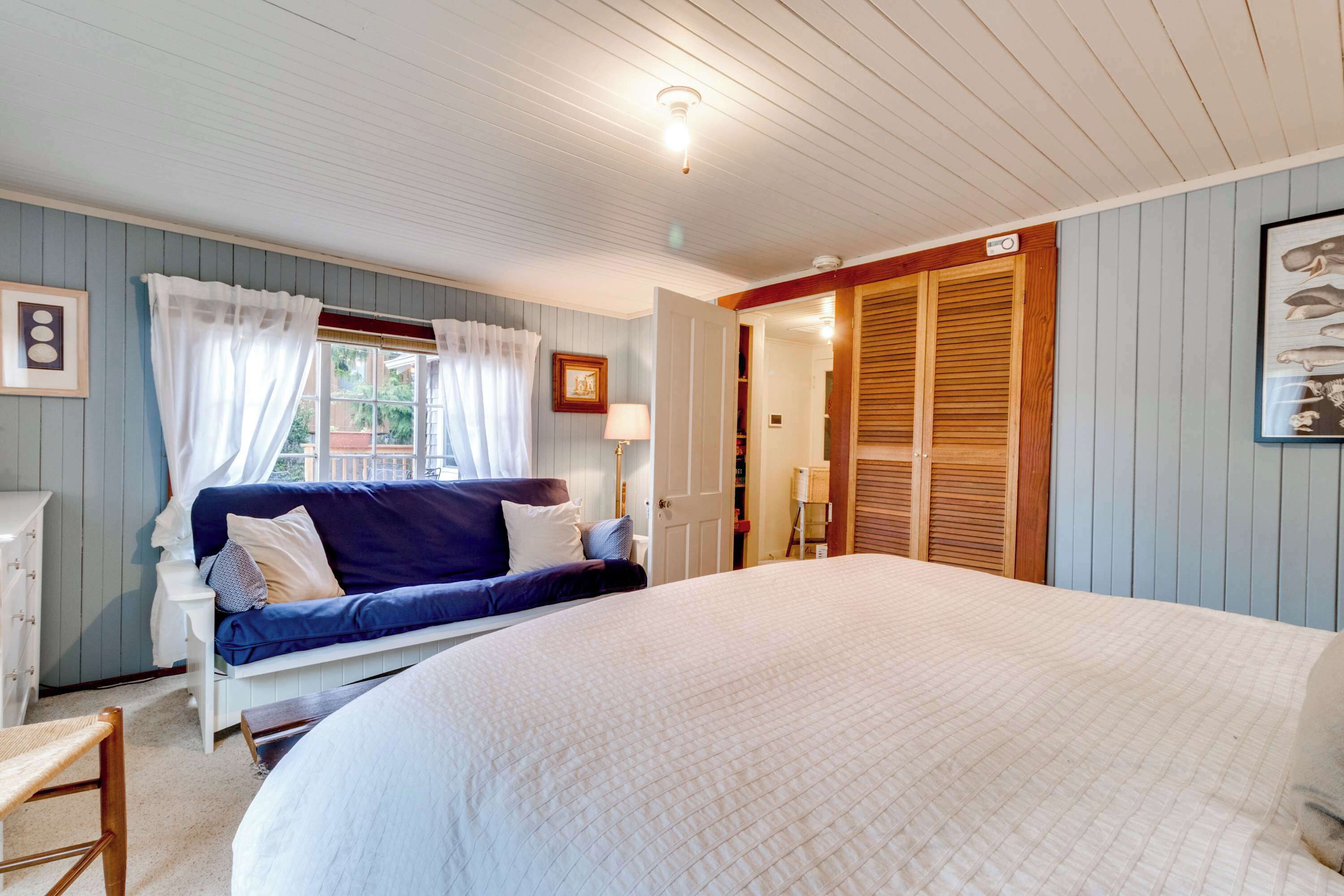 Une chambre à coucher avec un lit, un canapé, une armoire et une fenêtre avec des rideaux.