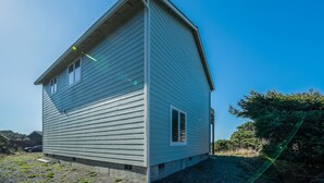 A single-story house with a gabled roof, a front door, and a small porch area. - Coastal cottage with stunning ocean views & private gas grill - dogs welcome (Gold Beach)