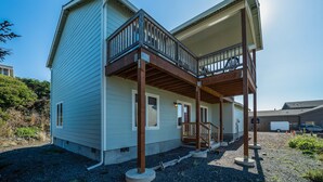 Ein zweistöckiges Haus mit überdachter Veranda und einer kleinen Treppe.