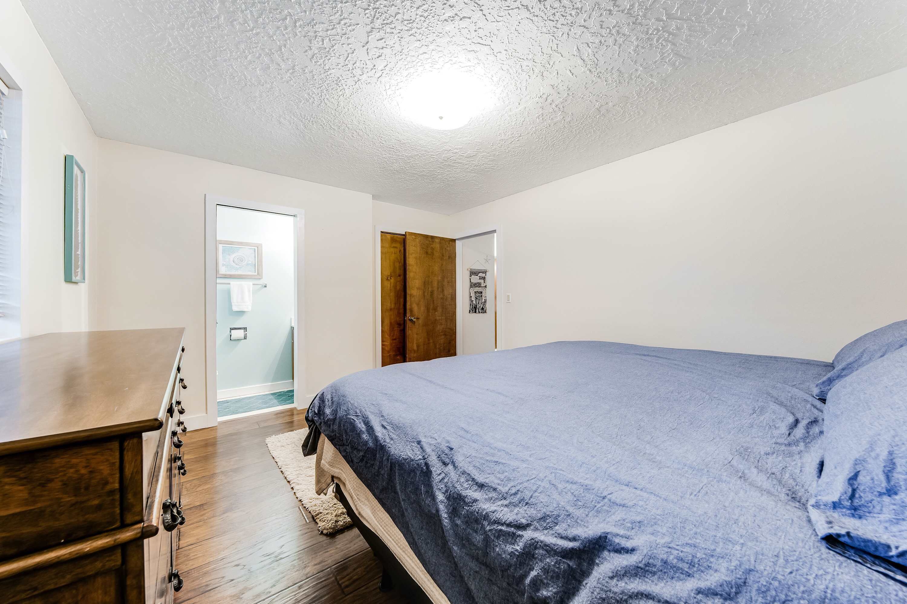 Een slaapkamer met een bed, een kaptafel en een deur naar een andere kamer.