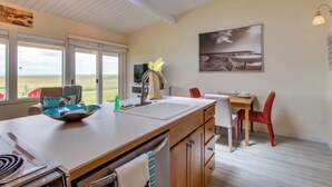 Una cocina moderna con una isla grande, una zona de comedor con sillas rojas y vistas al exterior.
