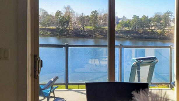 Une pièce avec vue sur un lac, une chaise et une petite table.
