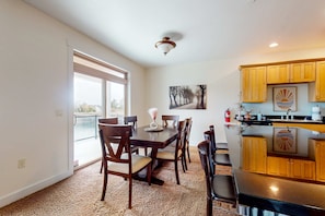 A dining area with a table and chairs, a kitchen with wooden cabinets, and a ceiling light fixture.