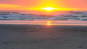 Une plage au coucher du soleil, avec des vagues et un ciel dégagé.