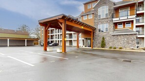 Un hôtel à plusieurs étages doté d’une entrée couverte, d’un parking et d’une façade en pierre.