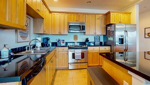 Une cuisine moderne avec des meubles en bois, des appareils électroménagers en acier inoxydable et un sol carrelé.