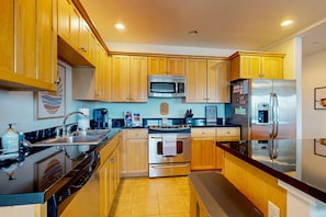 A modern kitchen with wooden cabinets, stainless steel appliances, and a tiled floor.