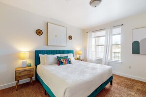 A neatly arranged bedroom with a large bed, two bedside tables, a headboard, and a window with curtains.
