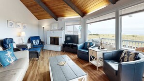 Una sala de estar con chimenea, televisor y vista al mar.