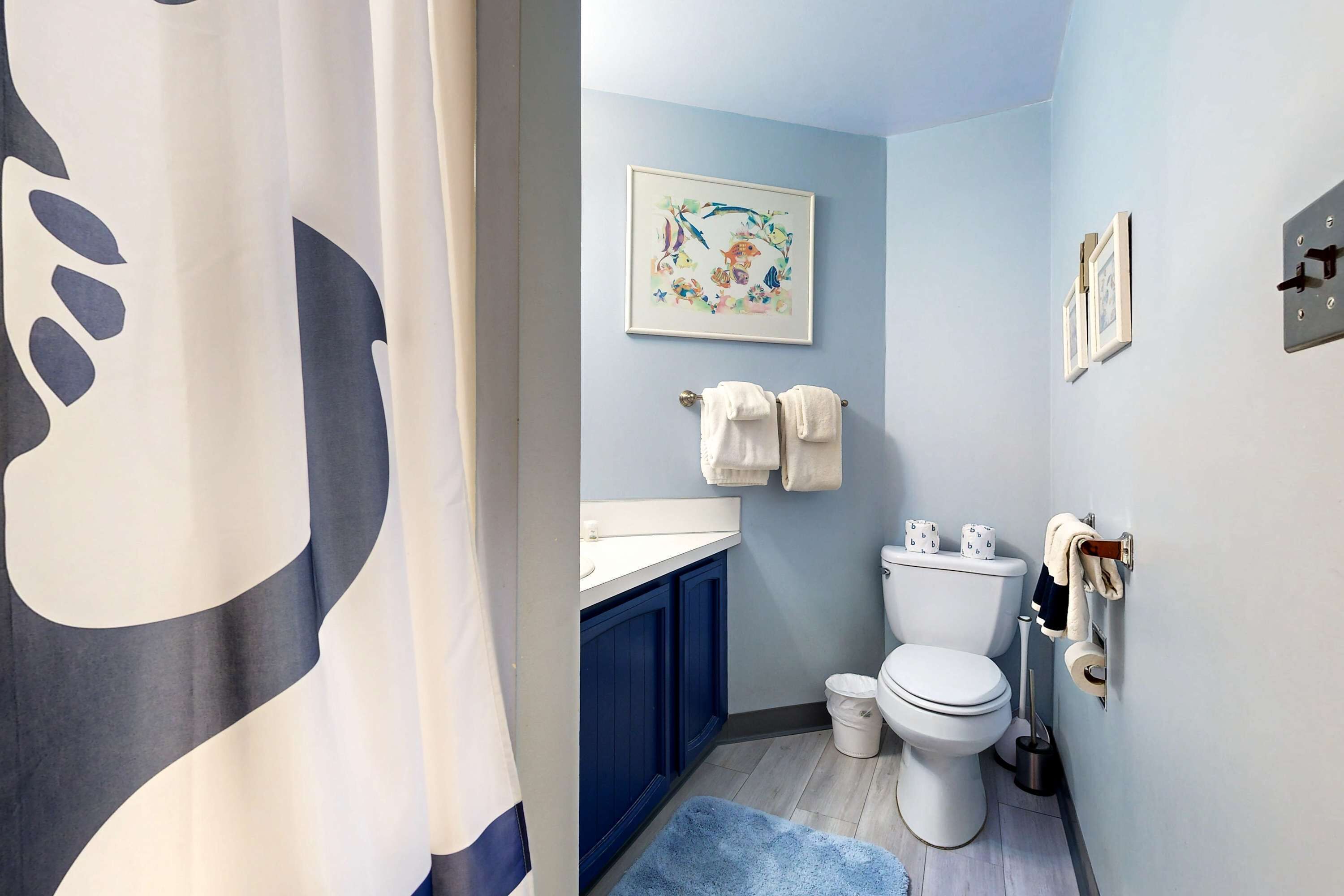 A bathroom with a toilet, sink, and blue cabinets.