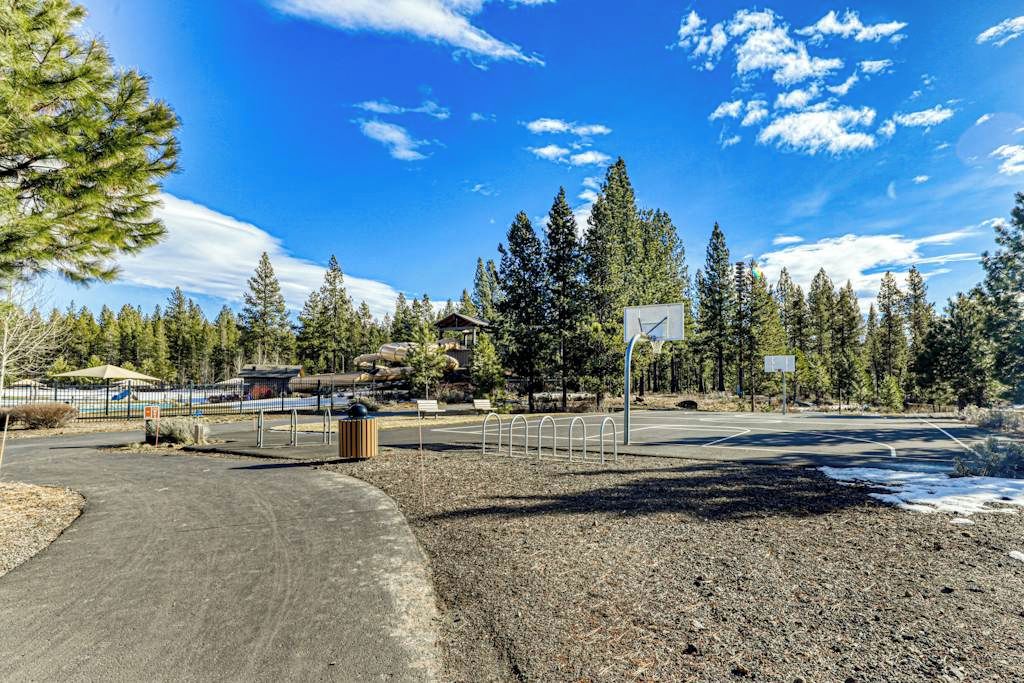 A parking lot with a dirt path leading to a building, surrounded by trees and a clear sky.